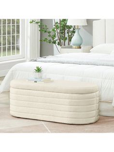 a white bed sitting next to a window with a plant on top of the bed