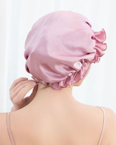 the back of a woman's head wearing a pink satin bonnet