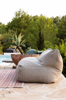 a bean bag sitting on top of a wooden deck next to a swimming pool with trees in the background