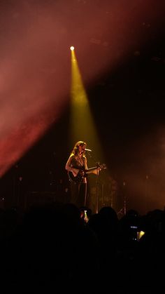 a man standing on top of a stage holding a guitar