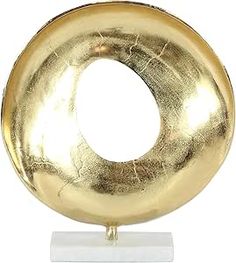 a gold plated metal object on a white stand