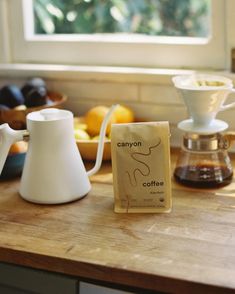 there is a coffee bag sitting on the counter next to some cups and saucers