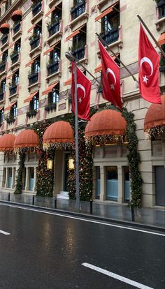 two red flags are in front of a building with christmas decorations on the windows and balconies