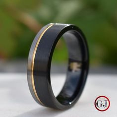 a black and gold wedding ring sitting on top of a table