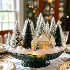 a christmas centerpiece with trees and lights in the shape of houses on a platter