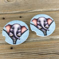 two stickers depicting an elephant with zippers on it's ears, sitting on a wooden surface