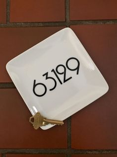 a white square plate with the number 599 on it and two keys attached to it