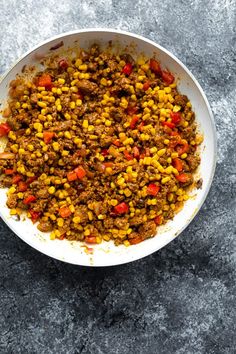 a white bowl filled with food on top of a gray countertop next to a spoon