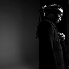 a man with dreadlocks standing in a dark room