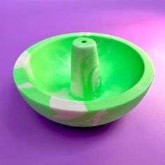 a green and white bowl sitting on top of a purple table