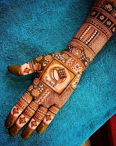 a hand that is decorated with henna and designs on the palm, sitting on a blue towel