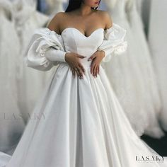 a woman in a white wedding dress standing next to dresses