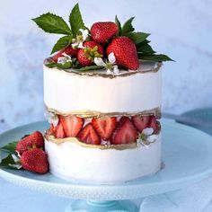 a three tiered cake with strawberries on top and flowers in the middle, sitting on a blue plate