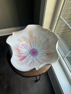 a white flower bowl sitting on top of a wooden table next to a window sill