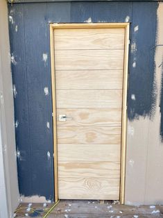 a wooden door in front of a blue wall with white paint on it's walls