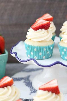 cupcakes with cream cheese frosting and fresh strawberries on the top are ready to be eaten