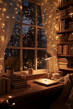 a desk with a laptop and books on it in front of a window filled with lights