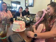 a group of people sitting around a table with a cake