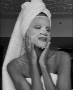 a woman with a towel on her head is shaving her face