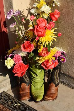 a pair of boots with flowers in them sitting on the ground next to a door