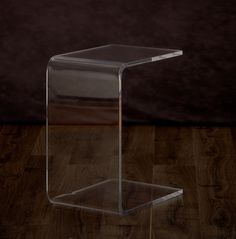 a clear plastic table sitting on top of a wooden floor next to a black wall