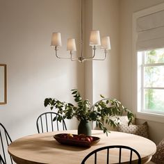 a dining room table with four chairs and a bowl of fruit on the table next to it