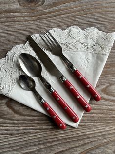 three red and white utensils are sitting on a napkin