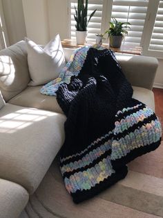 a couch with a blanket on top of it next to a potted plant and window