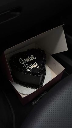 a heart shaped cake sitting inside of a box on top of a car dash board