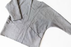 an unbuttoned gray shirt laying on top of a white surface with one button undone