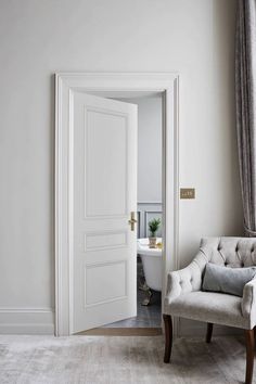 an open door leading to a bathroom with a tub and chair in it's corner