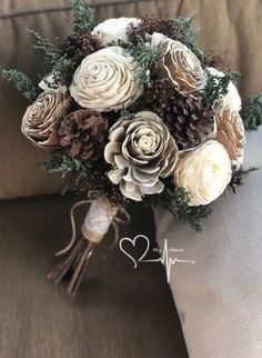 a bridal bouquet sitting on top of a couch with pine cones and other flowers