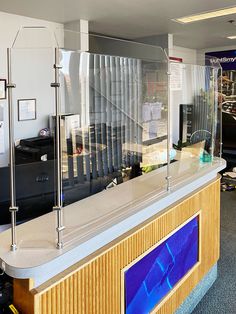 an office with a glass counter top next to a wall mounted tv and computer equipment