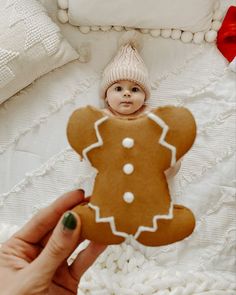 a person holding up a gingerbread cutout in front of a white bed sheet