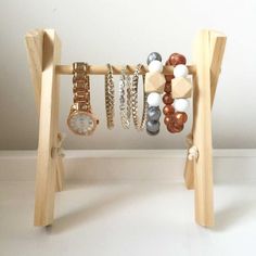 a wooden stand with bracelets and watches on it's sides, in front of a white wall