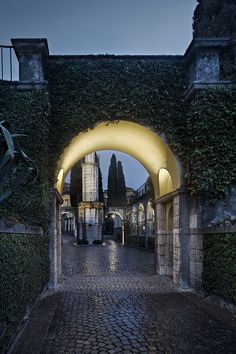 an archway leading to a building with a clock tower in the background at night time