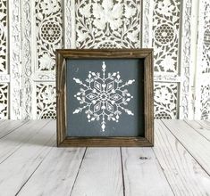 a snowflake cut out in a wooden frame on a white wood table top