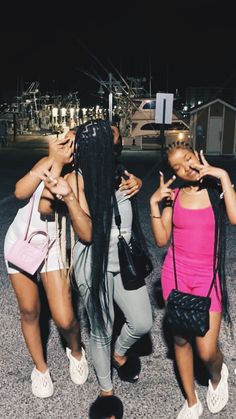 three young women standing next to each other in the middle of a street at night