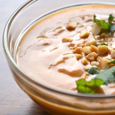 a glass bowl filled with soup and garnished with green leaves