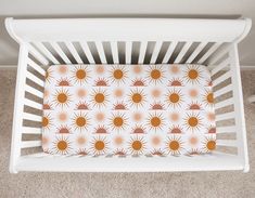 a white crib with an orange and yellow sun print