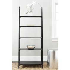 a black shelf with white flowers and a bowl on it in front of a window