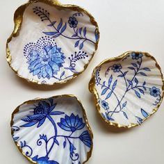 three blue and white plates sitting on top of a table next to each other with gold rims