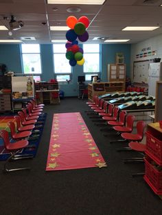 an empty classroom filled with lots of desks and balloons hanging from the ceiling above them