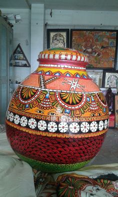 a large colorful vase sitting on top of a table next to other art work and paintings