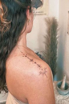 the back of a woman's shoulder with an arrow and stars tattoo on it