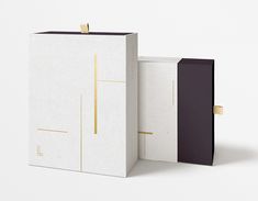 two white boxes with black and gold designs on the front one has a square opening