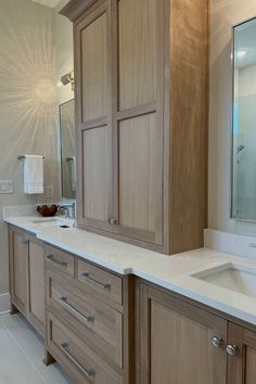 a large bathroom with two sinks and wooden cabinetry in it's center area