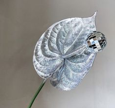 a silver flower with a mirror ball in it's center, on a gray background