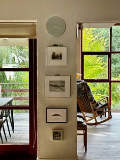 a clock mounted to the side of a wall next to a wooden table and chairs