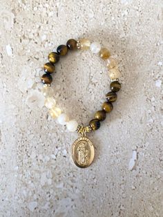 Saint Francis Bracelet featuring 8MM smooth golden tiger eye and gold rutilated quartz stones accented with gold spacers and Saint Francis of Assisi Medal.  Saint Francis is known to be the patron Saint for pets and animals.  Bracelet is beaded on stretch cord and measures 7 inches. GIFT BOXED Gold Beaded Rosary Bracelet For Healing, Gold Spiritual Stretch Bracelet With Gemstone Beads, Gold Spiritual Crystal Bracelet With Natural Stones, Gold Citrine Round Beaded Bracelets, Spiritual Gold Charm Bracelet With Gemstones, Spiritual Gold Beaded Bracelets With Charms, Spiritual Gold Gemstone Charm Bracelet, Gold Citrine Beaded Bracelet With Gemstone Beads, Gold Citrine Gemstone Beaded Bracelets